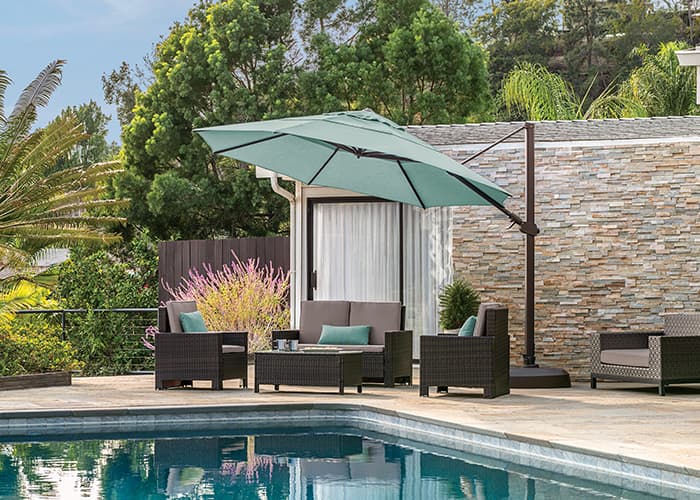blue cantilver umbrella over a conversation set by a pool